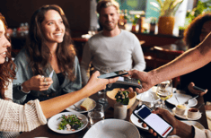 Happy customers paying for their meals by card at a restaurant