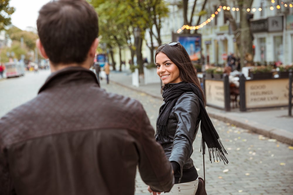 Woman holds hand with his partner as she longing stares at him.